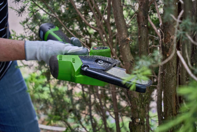 A man is sawing a tree with a mini chainsaw